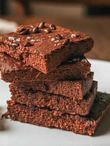 Des carrés de brownie patate douce dans une assiette blanche, sur une table en bois.