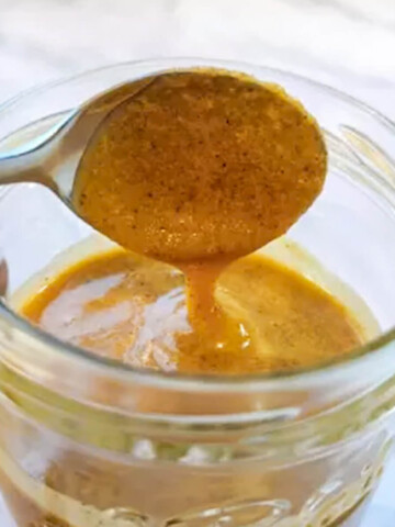 Une cuillère avec du praliné noisette fait maison, au dessus d'un pot de confiture.