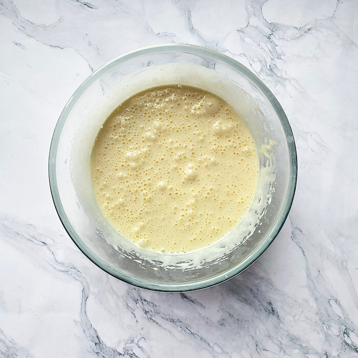Blanchir-oeufs-sucre-molly-cake Mélange d'œufs et de sucre blanchi dans un bol en verre, une étape clé pour réussir la base aérienne d'un Molly Cake.
