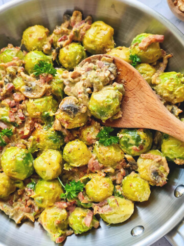 Une poêlée de choux de Bruxelles, lardons et champignons dans une poêle en inox, cuillère en bois.