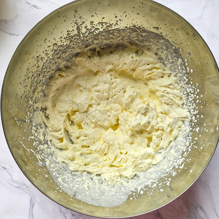 faire-chantilly-ferme Crème chantilly fouettée bien ferme dans un bol en inox, présentant une texture onctueuse.