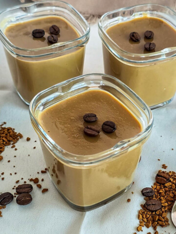 Des crèmes dessert au café soluble, grains de café et café soluble sur le coté.