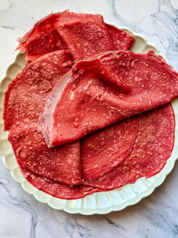 Des wraps de betterave posés dans une assiette blanche, sur un fond marbré blanc.