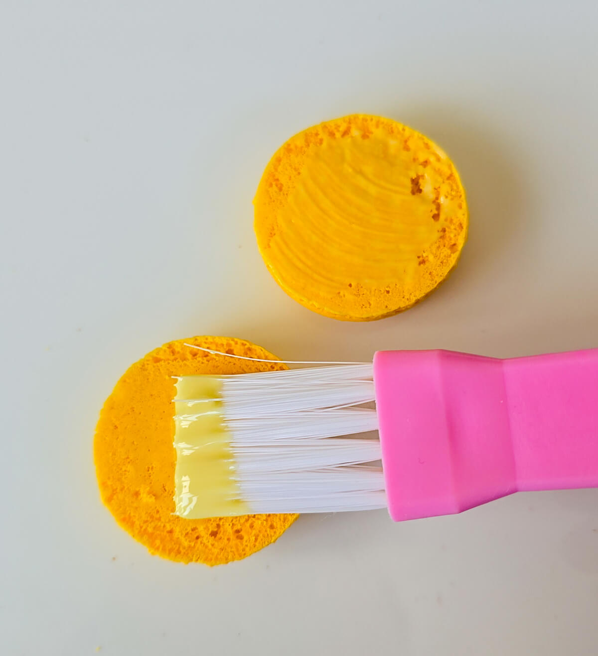 extrait-citron-coque-macaron Application au pinceau de cuisine d'un sirop de citron sur l'intérieur d'une coque de macaron jaune pour intensifier le goût acide et parfumer le biscuit.