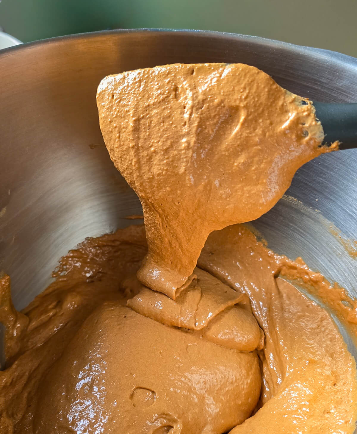 macaronnage-macarons-café Étape du macaronnage dans un cul-de-poule en inox : mélange de la meringue marron claire et de la poudre d'amande avec une maryse noire pour obtenir un ruban lisse.