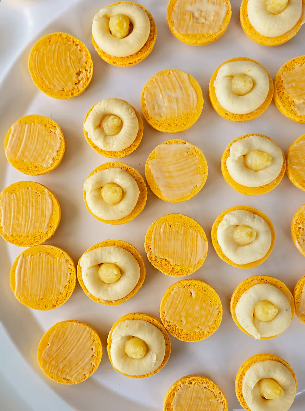 pochage-macarons-citron Montage des macarons au citron : coques retournées garnies d'un cercle de ganache montée au citron et d'un cœur fondant de lemon curd au centre.