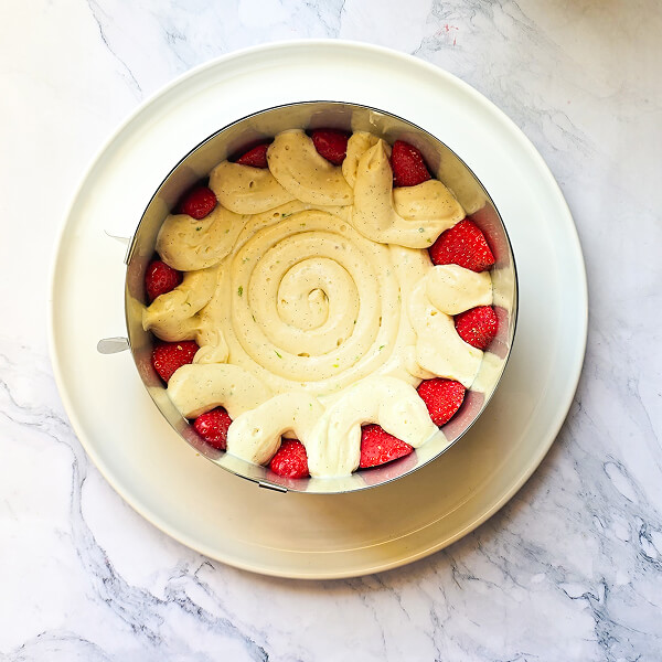 3-montage-fraisier-creme-diplomate un cercle à pâtisserie avec de la crème diplomate et des fraises coupées en deux sur les bords.