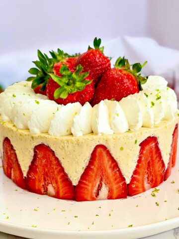 Un fraisier léger et facile avec des fraises fraîches coupées en deux disposées sur tout le pourtour, garni d'une crème diplomate au citron vert, de dômes de chantilly pochés et de fraises entières sur le dessus avec quelques zestes de citron vert.