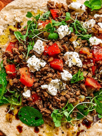 Un wrap de boeuf haché, feta, tomates, sur une planche de bois.