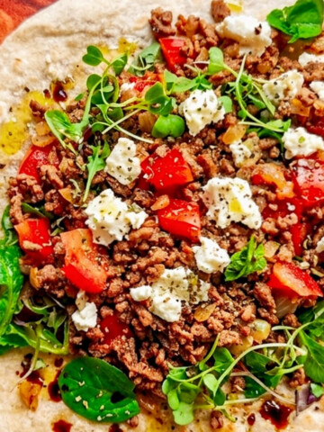 Un wrap de boeuf haché, feta, tomates, sur une planche de bois.